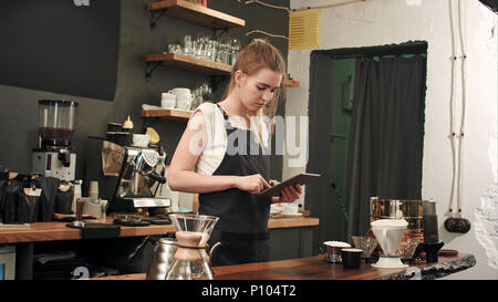 Happy barista oder Kellner in Schürze mit Tablet-PC Computer an der Bar oder im Café Stockfoto