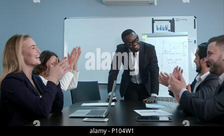 Multi-ethnische Gruppe grüßt afro-amerikanischen Boss mit Klatschen und lächelnd Stockfoto