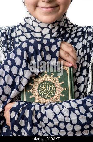 Junge muslimische Mädchen umarmt heilige Buch der Koran Stockfoto