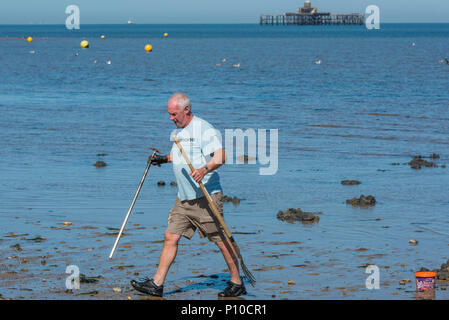 Ein Fischer auf der Suche nach wattwürmer Angeln Köder in Herne Bay, Kent, England, UK zu verwenden. Stockfoto