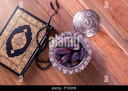 Termine mit Rosenkranz und Heiligen Quran auf hölzernen Hintergrund der Ansicht von oben - Ramadan Kareem/Eid al Fitr Konzept Stockfoto