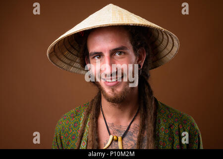 Junge schöne Hispanic Mann mit Dreadlocks gegen Braun backgr Stockfoto