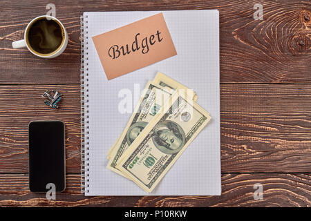 Accounting Notepad, Geld und Accessoires. Leere Notepad, Geld, Smartphone und die Tasse Kaffee. Stockfoto