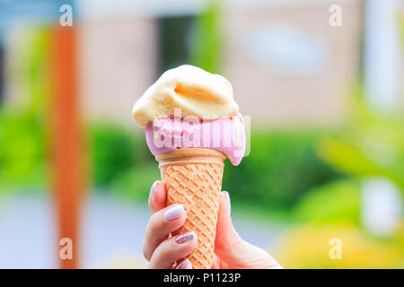 Weibliche hand Eis in der Waffel Kegel gegen blur Hintergrund Stockfoto