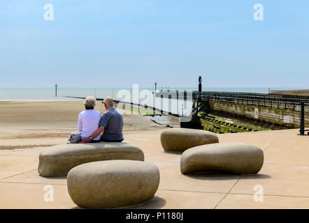 Ansicht der Rückseite des älteren Paares auf einige große Steine, von denen aus man Meer sitzen Stockfoto