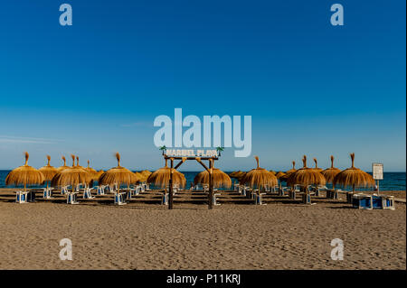 Liegestühle unter Sonnenschirmen am Strand in der Axarquía gestapelt, La Cala del Moral Gemeinde von Rincón de la Victoria, Spanien mit kopieren. Stockfoto