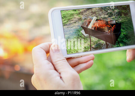 Die menschliche Hand ist, die Bilder von der Brand auf dem Smartphone. Im Freien. Close-up. Stockfoto