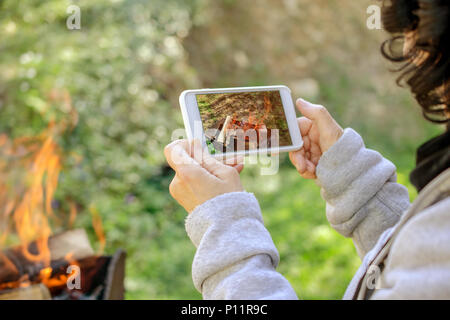 Die Frau ist, die Bilder von der Feuerwehr auf Ihrem Smartphone. Im Freien. Close-up. Stockfoto