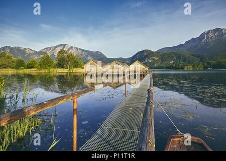 Blick auf den Kochelsee mit hölzernen Bootshäuser gegen Mountain Range - Bayern, Deutschland Stockfoto