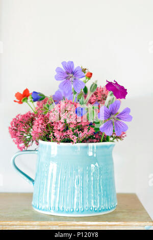 Blau steinzeug Krug mit hübschen Garten Blumen auf einem kaminsims Stockfoto