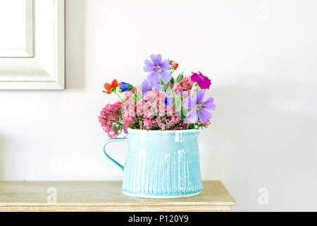 Blau steinzeug Krug mit hübschen Garten Blumen auf einem kaminsims Stockfoto