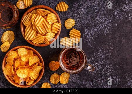 Bier und knusprige Kartoffelchips auf Stein Hintergrund. Ansicht von oben, kopieren. Stockfoto