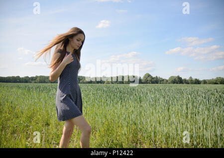 Zierliche Frau Wandern auf der Wiese neben dem Feld Struktur. Weibliche Model und Natur. Stockfoto