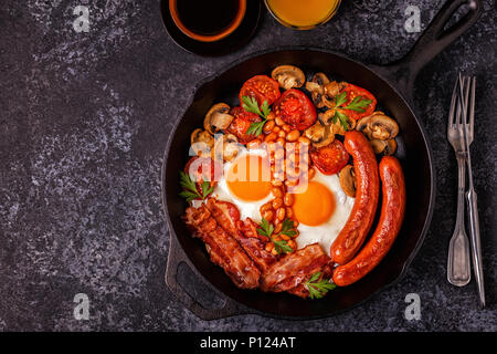 Traditionelles Englisches Frühstück mit Spiegelei, Würstchen, Bohnen, Pilze, gegrillten Tomaten und Speck. Ansicht von oben. Stockfoto