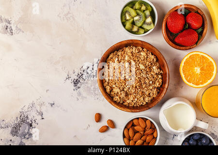 Gesundes Frühstück - Schüssel Müsli, Beeren und Obst, Nüsse, Orangensaft, Milch, Ansicht von oben. Stockfoto