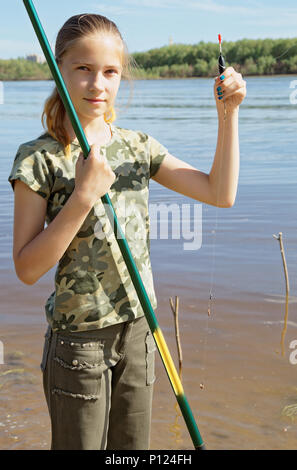 Jugendlich Fischer bereitet die Köder der Köder in den Fluss zu werfen. Eröffnung der Angelsaison, einem seltenen Hobby für ein Mädchen Stockfoto