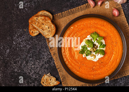 Kürbis und Karotten Suppe mit Sahne, Samen und Petersilie. Ansicht von oben. Stockfoto