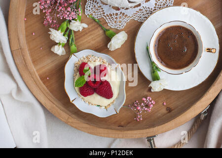 Eine hölzerne Fach mit Frühstück und duftenden Kaffee. Himbeere Beeren und Blumen. Helle Farben. Romantik. Guten Morgen. Für Text platzieren. Blick von oben. Stockfoto
