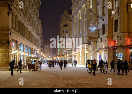 Fußgänger gehen auf einem schneebedeckten Vaci utca in Budapest im Winter bei Nacht Stockfoto