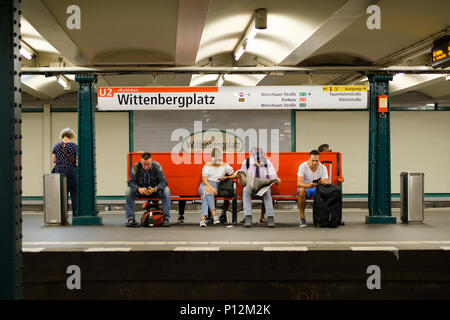 Berlin, Deutschland - Juni, 2018: Man sitzt auf der Bank slooking am Handy, während für die U-Bahn am Wittenbergplatz Station in Berlin warten, Stockfoto