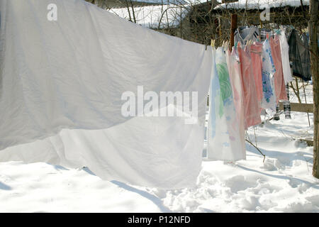 Wäsche aufhängen auf einfache Wäscheleine im Hof, im Winter Stockfoto