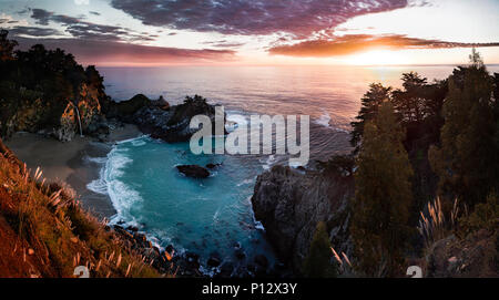 Sonnenuntergang mit Strand, Bucht, Wald und Wasserfall. McWay Falls, Big Sur, Kalifornien Stockfoto