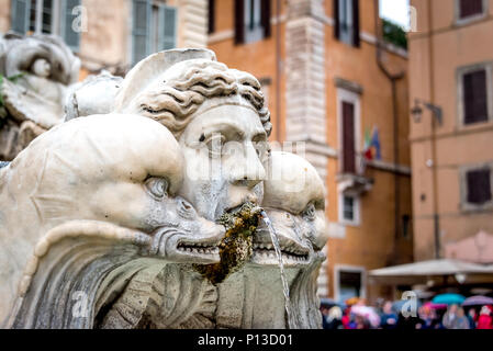 Angesichts einer Triton mit zwei Delphinen in Fontana del Moro/Moor Brunnen auf der Piazza Navona, Rom, Italien, mit bunten touristische Sonnenschirme und orangen Wänden Stockfoto