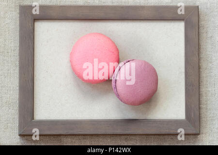 Zwei frisch geschnittete Makronen von rosa und violetten Farben in Holzrahmen, ungewöhnliche abstrakte süße Kunst Stockfoto