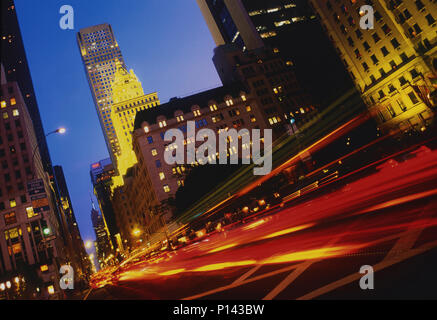 New York City auf der 5th Ave, die, mit Verkehr Streifen und beleuchteten Gebäuden in der Dämmerung, New York, NY, USA Stockfoto