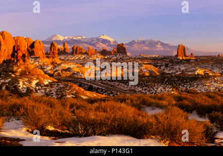 Arches National Park: In der Nähe von Moab, Blick auf den fernen Horizont durch Felsformationen über Schnee bedeckte Wüste im späten Licht, Utah, USA Stockfoto