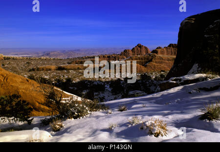 Arches National Park: In der Nähe von Moab, Blick auf den Canyon und Felsformationen über Schnee bedeckte Wüste in der Dämmerung mit cloudscape, Utah, USA Stockfoto