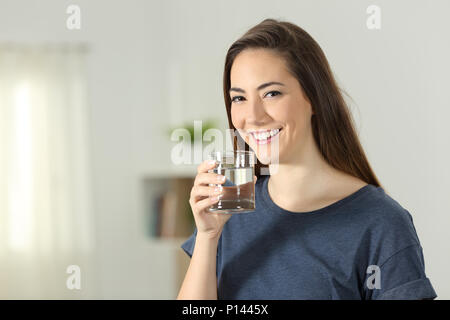 Happy girl Holding ein transparentes Glas Wasser stehend zu Hause Stockfoto