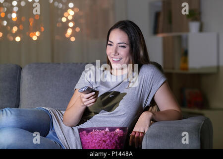 Glückliche Frau Fernsehen Inhalt in der Nacht auf einer Couch im Wohnzimmer zu Hause sitzen Stockfoto