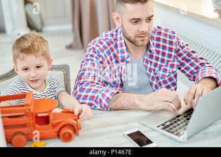 Junger Vater von zu Hause aus arbeiten Stockfoto