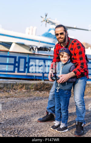 Vater und Sohn holding Fernbedienung Steuerknüppel und Pilotierung quadrocopter Stockfoto