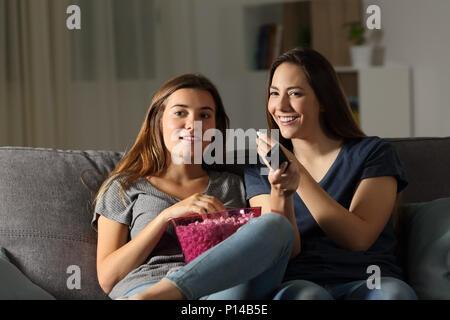 Zwei glückliche Mitbewohner wathing tv in der Nacht auf einer Couch im Wohnzimmer zu Hause sitzen Stockfoto