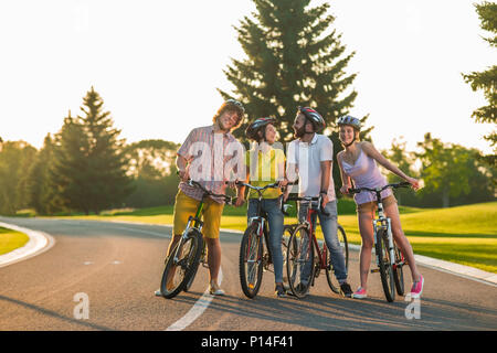 Gruppe von Freunden Spaß im Freien. Vier Glückliche Schüler mit Fahrrädern auf der Straße. Genießen Sie ihre Radfahren mehr. Stockfoto