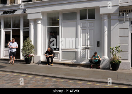 Die Leute draußen sitzen Shop mit mobiuole Telefone, Covent Garden, London, England, Großbritannien Stockfoto