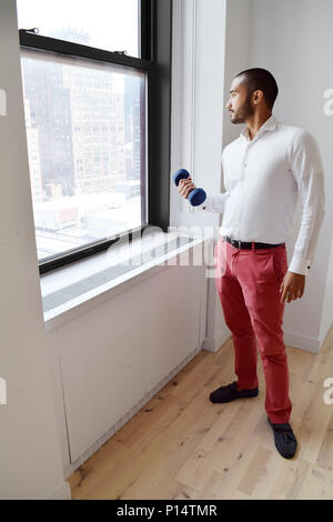 Stattliche Hispanic (Latino) Geschäftsmann, Gewichte zu heben in der Turnhalle neben einem Fenster Stockfoto