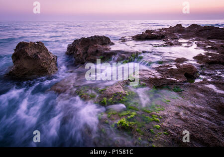 Dämmerung an einem felsigen Strand voller Abschaum, palmahim Strand Israel Stockfoto