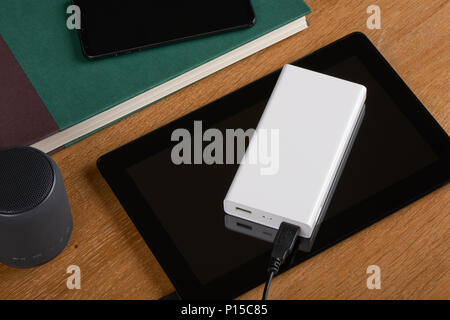 Weiß externe Akku (Power Bank) aufladen Tablet-PC auf einem hölzernen Hintergrund Stockfoto