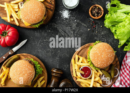 Burger, Hamburger, Pommes Frites und frischem Gemüse. BBQ party food. Dunkler Hintergrund, Ansicht von oben kopieren und Platz für Text. Sommer Grill Konzept Stockfoto