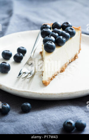 Scheibe des klassischen New York Cheesecake mit frischen Blaubeeren gekrönt. Detailansicht, selektiver Fokus Stockfoto