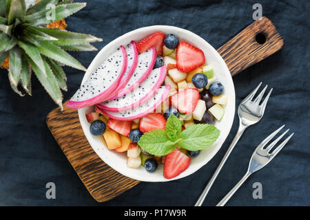 Obstsalat mit tropischen Früchten pitaya in eine Schüssel geben. Ansicht von oben. Gesunde Ernährung, gesunde Lebensweise Konzept Stockfoto