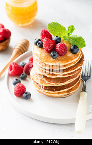 Pfannkuchen mit Beeren, Honig und Minze auf weiße Platte, Detailansicht, selektive konzentrieren. Stapel Pfannkuchen. Leckeres Dessert oder Frühstück Stockfoto