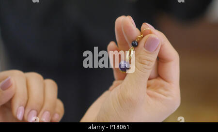 Weibliche hand mit Armband auf it Holding entwickelt, Ohrring Stockfoto