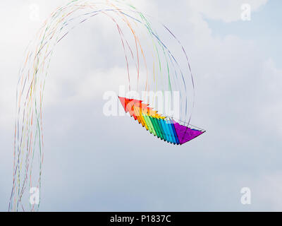 Stapel von 16 2-line delta Lenkdrachen mit langen Schwänzen in den Farben des Regenbogens fliegen. Stockfoto