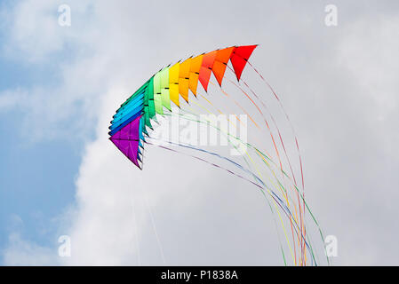 Stapel von 16 2-line delta Lenkdrachen mit langen Schwänzen in den Farben des Regenbogens fliegen. Stockfoto