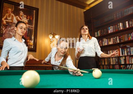 Junge Frauen spielen Billard im Büro nach der Arbeit. Stockfoto