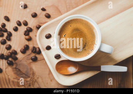 Tasse Kaffee serviert auf einem Tablett aus Holz mit einem Holzlöffel und Kaffeebohnen. Ansicht von oben, flach Stockfoto